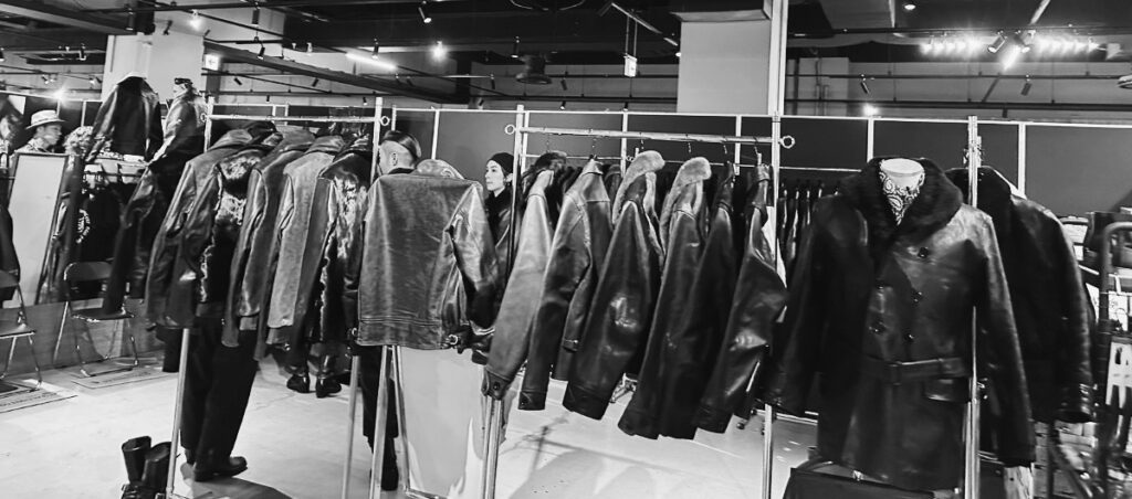 レザージャケットが整然と並ぶ展示ブース。来場者が製品を見比べている様子。