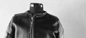 シボ感のあるブラックレザーを使用したノーカラー(襟なし)ライダースジャケット。ミニマルで都会的なデザインが特徴。